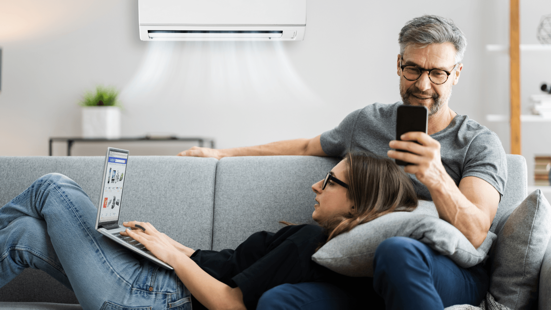 A happy couple sits on their lounge enjoying air conditioning comfor