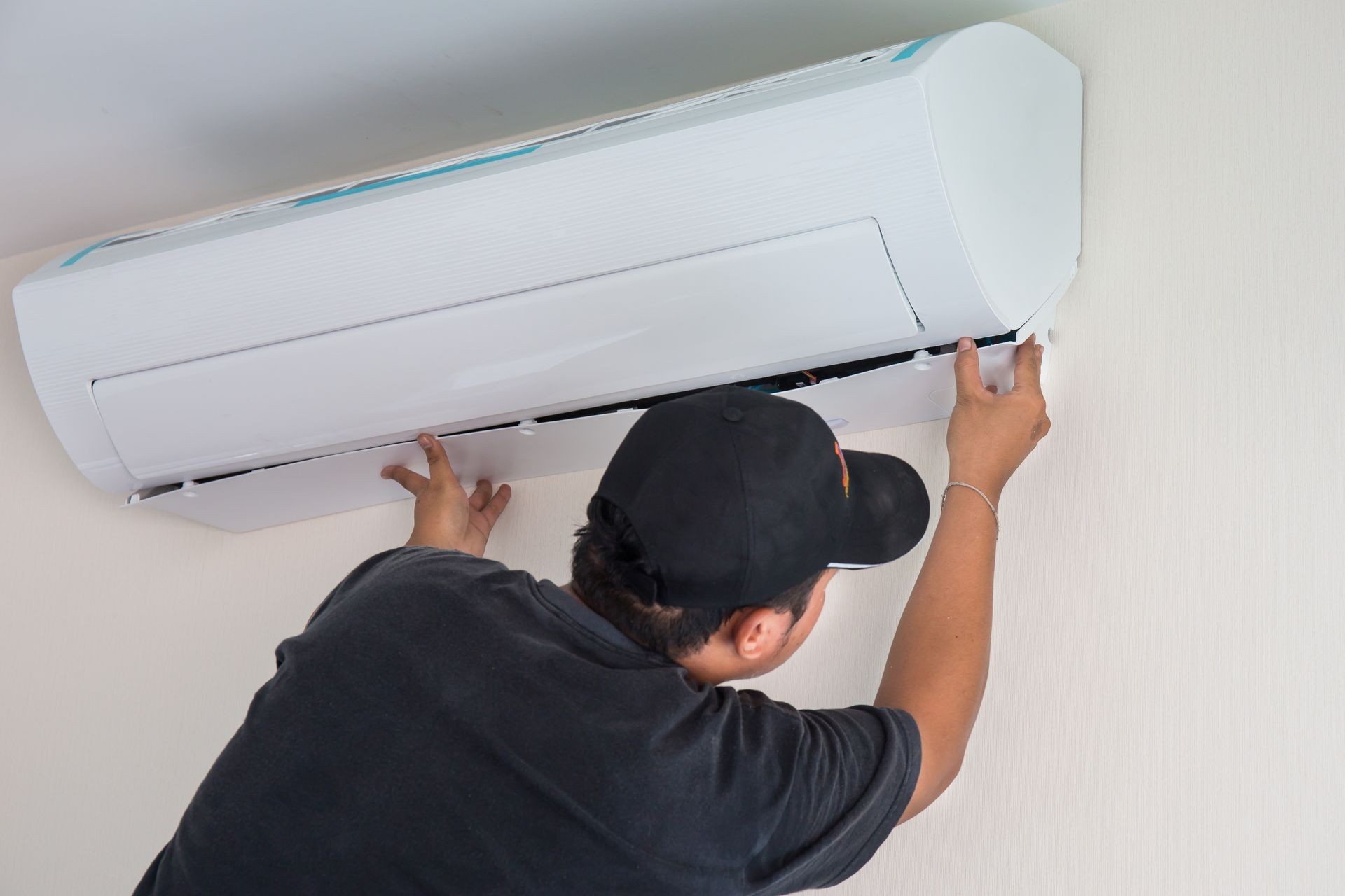 Man worker installs indoor air conditioner in the new home. Select focus