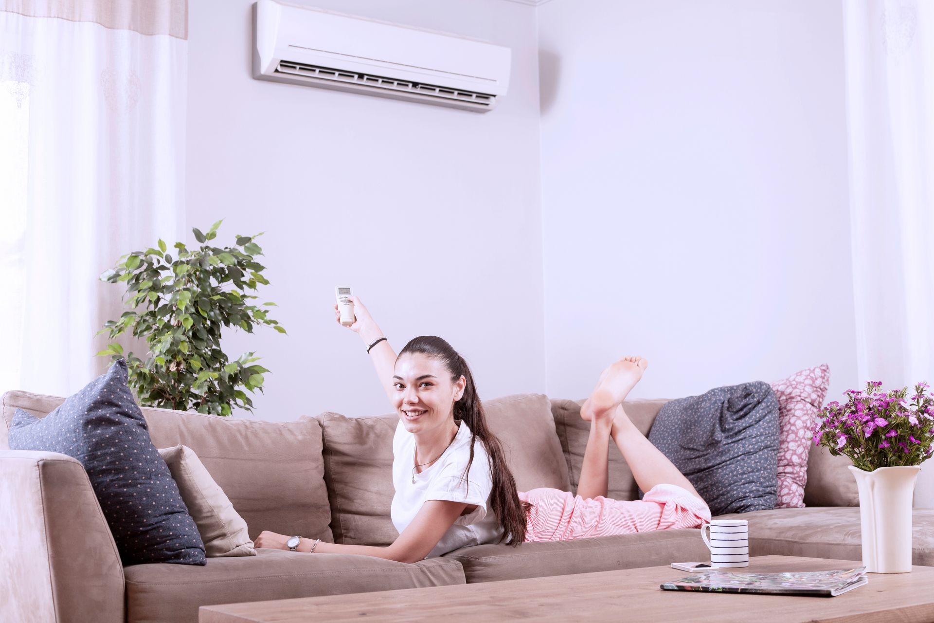 woman using remote control of air conditioner
