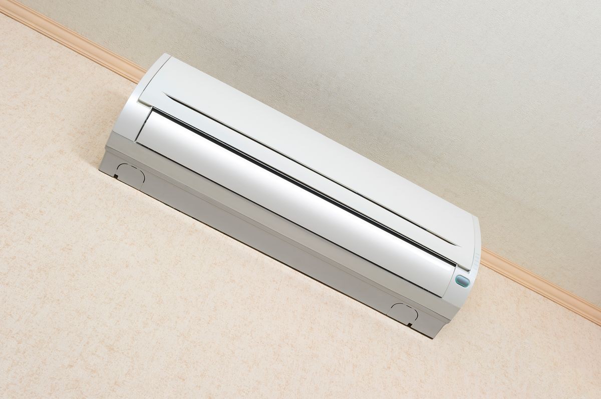 Air conditioner of white color on wall background, split-system in apartment with textured wallpaper, temperature control in hot weather, comfortable living conditions