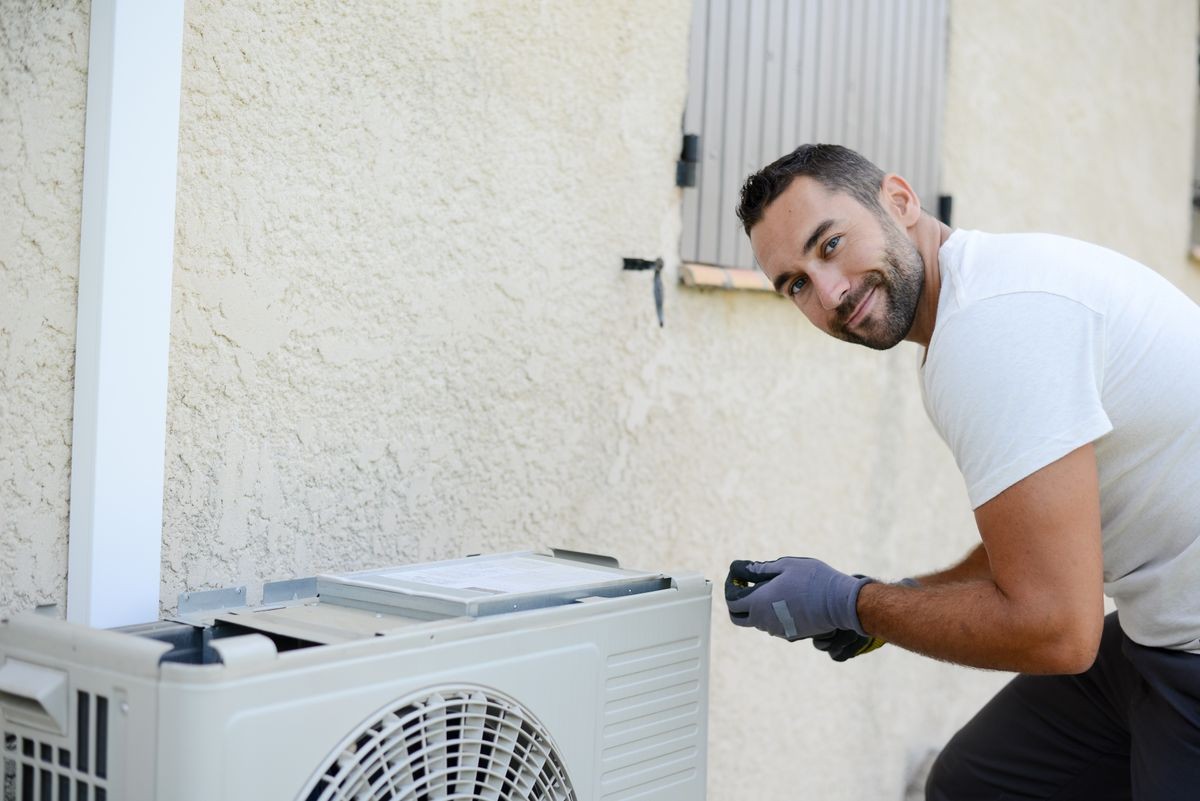 handsome young man electrician installing an air conditioning in a client house